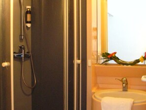 Un baño con ducha, lavamanos y espejo.