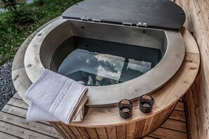 Ein Whirlpool mit Holzterrasse, einem Handtuch und zwei Kerzen.