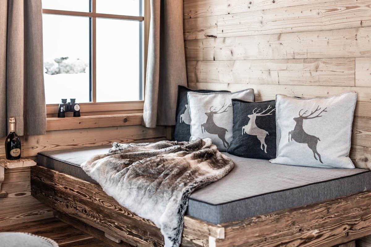 Una habitación acogedora con una cama de madera, una manta de piel sintética y almohadas con estampados de ciervos.
