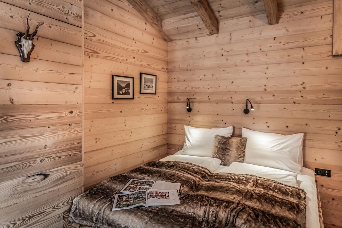 Una habitación de cabaña de madera con una cama, una manta y un cráneo de venado en la pared.