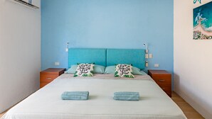 A bedroom with a blue headboard, two pillows with 'Live and Love' text, a bed with two towels, and a wall-mounted air conditioner. - Casa Menta (Puerto Escondido)