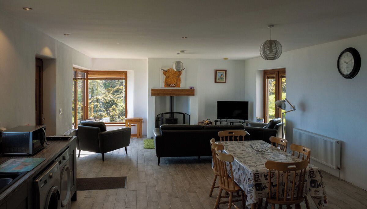 Ein Wohnzimmer mit einer Couch, einem Esstisch mit Stühlen, einem Fernseher und einem Kamin.