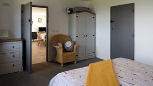 A bedroom with a bed, a chair, a wardrobe, and a desk. - Makem's Self Catering Cottage (Ballycastle)