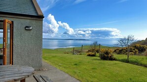 A coastal house with a grassy yard and a view of the sea. - Makem's Self Catering Cottage (Ballycastle)
