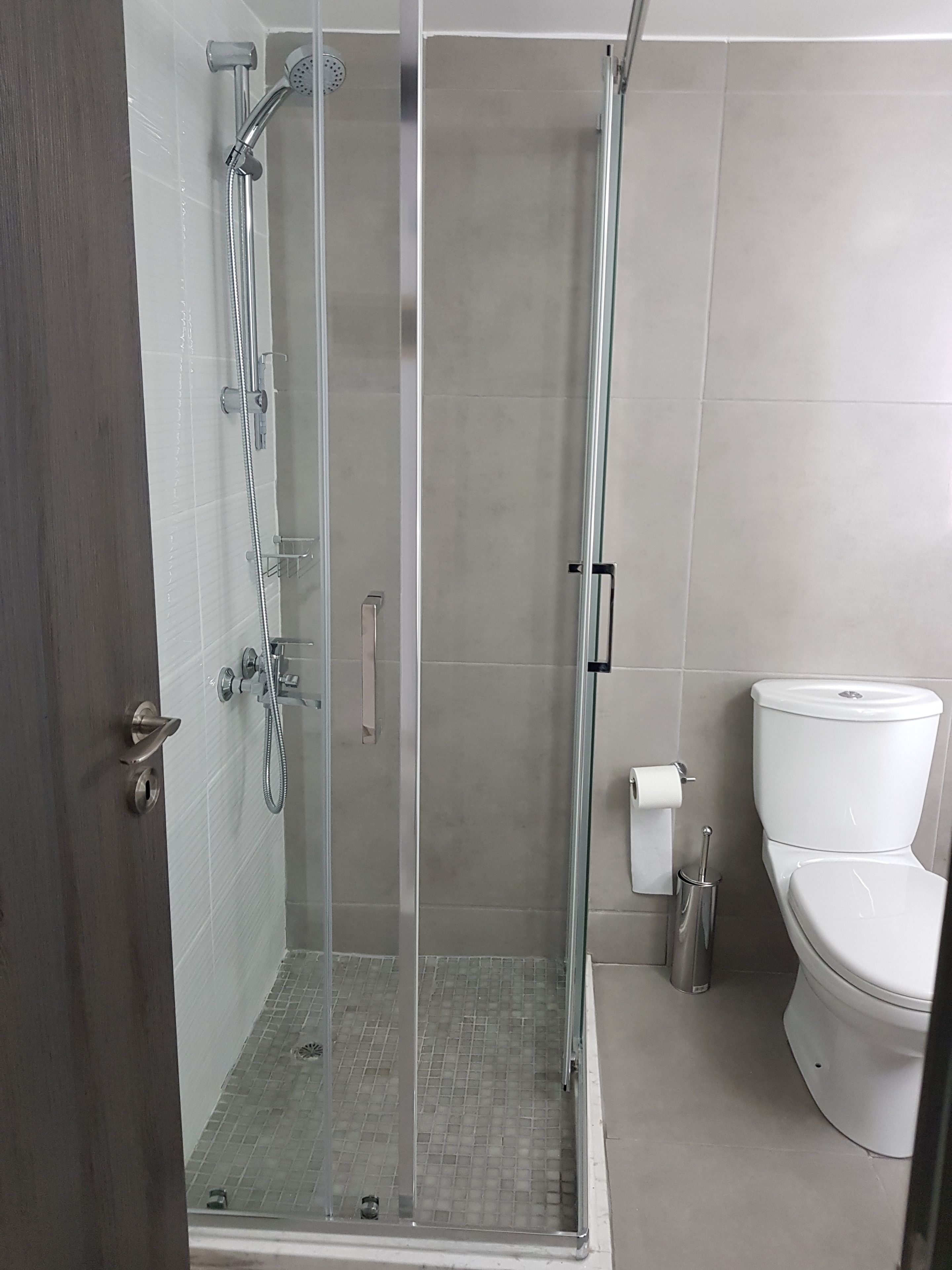 Een moderne badkamer met een glazen douchecabine, toilet en een bidet.