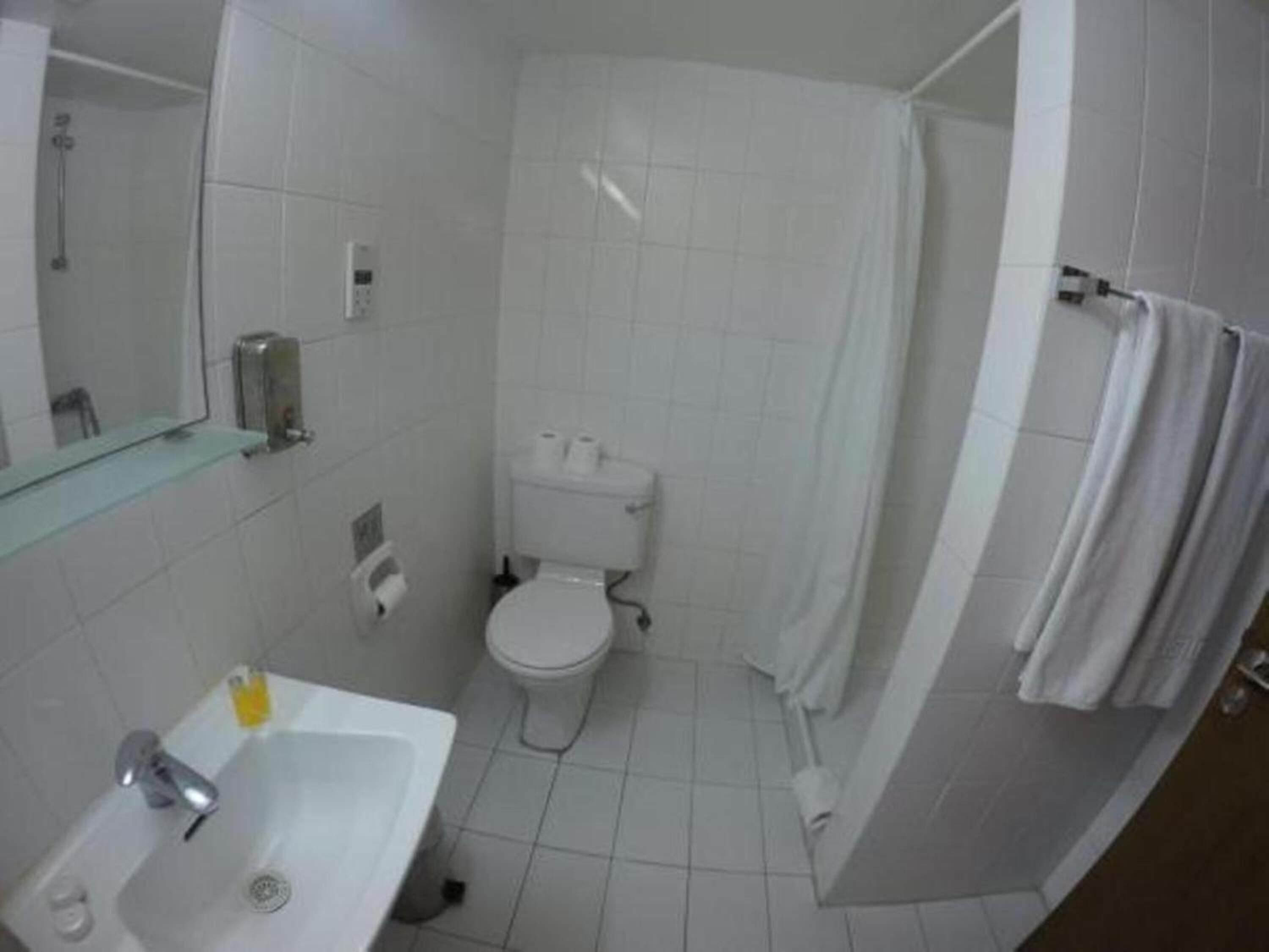 Un baño con lavabo blanco, inodoro y zona de ducha.