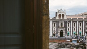 A historic building with a prominent clock tower, arched doorways, and a courtyard with ruins. - Agatha Hotel (Catania)