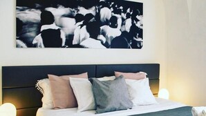 A neatly made bed with a dark headboard, multiple pillows in various colors, and rolled towels on the bed. - Agatha Hotel (Catania)