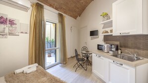 A compact kitchen with a dining area, a large window with curtains, and a flat-screen TV mounted above the counter. - Prima dell'Elba Bed & Breakfast (Piombino)