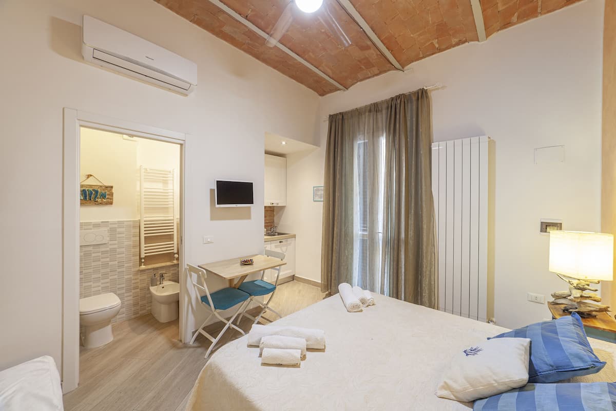 A hotel room with a bed, a desk, a chair, a television, and a bathroom.