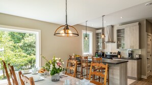 Une cuisine moderne avec des meubles en bois, un îlot central et un coin repas avec une table dressée pour quatre personnes.