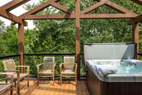 Une terrasse en bois avec deux chaises en bois et un jacuzzi.