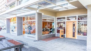 A modern building with large glass windows and a stone-paved entrance. - Estudio A 20M Del Centro Cívico (San Carlos de Bariloche)