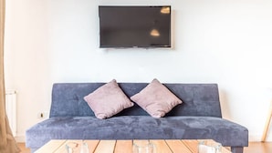 A modern living room with a grey sofa, two cushions, and a wooden coffee table with two clear glass vases. - Estudio A 20M Del Centro Cívico (San Carlos de Bariloche)