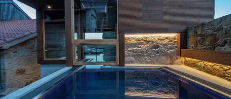 Un edificio moderno con puerta de vidrio, pared de piedra y piscina.