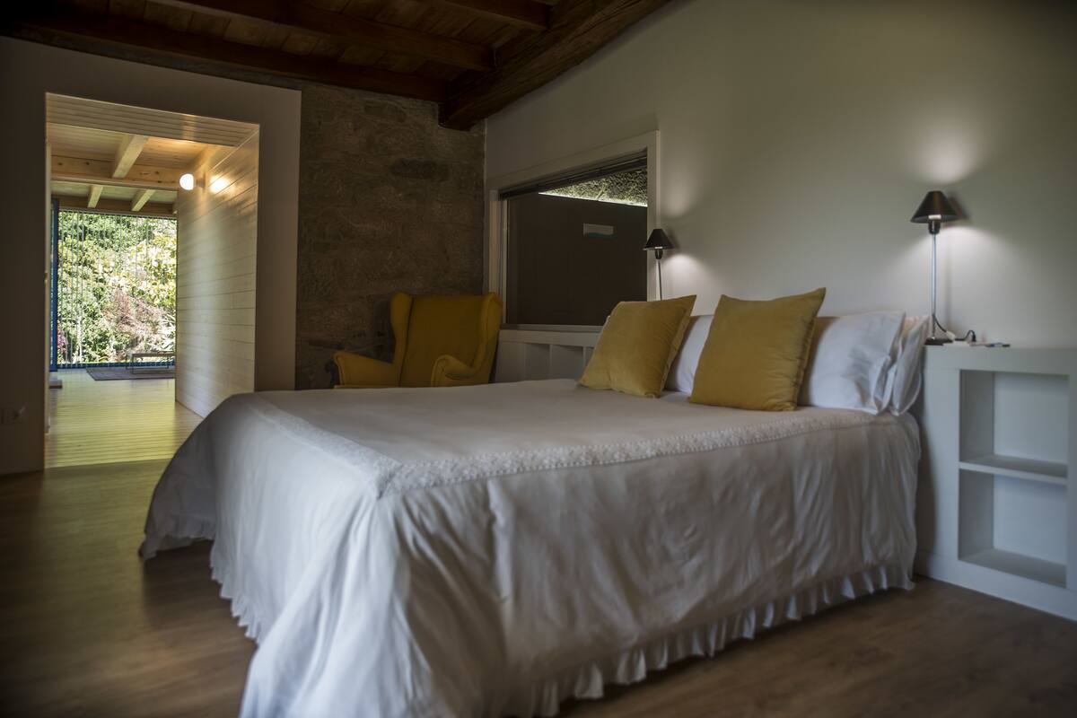 Une chambre avec un grand lit, deux lampes de chevet et une vue sur un balcon.