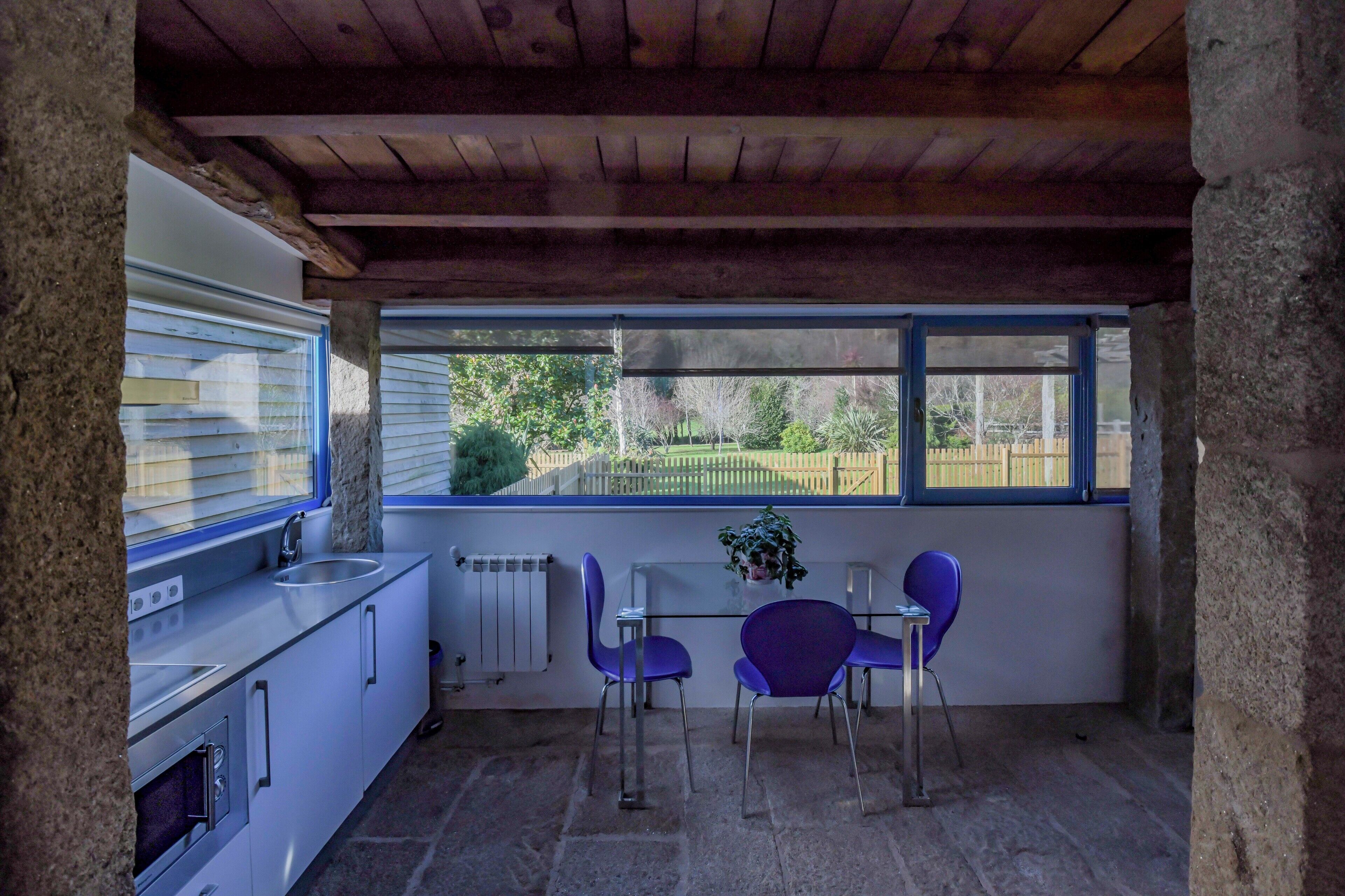 Una cocina con ventana, un lavamanos y una mesa con dos sillas.