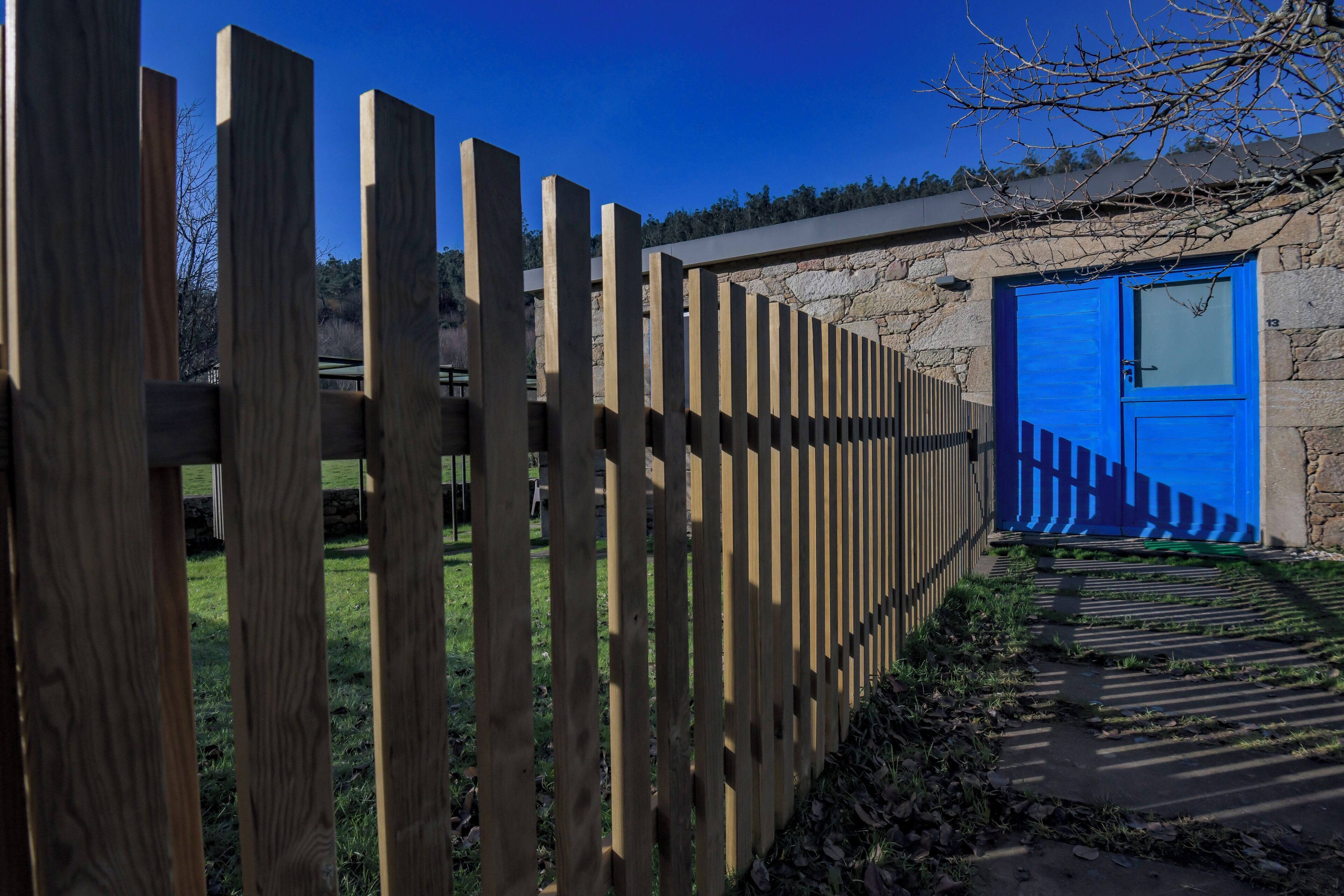 A wooden fence, a blue door, and a stone wall.