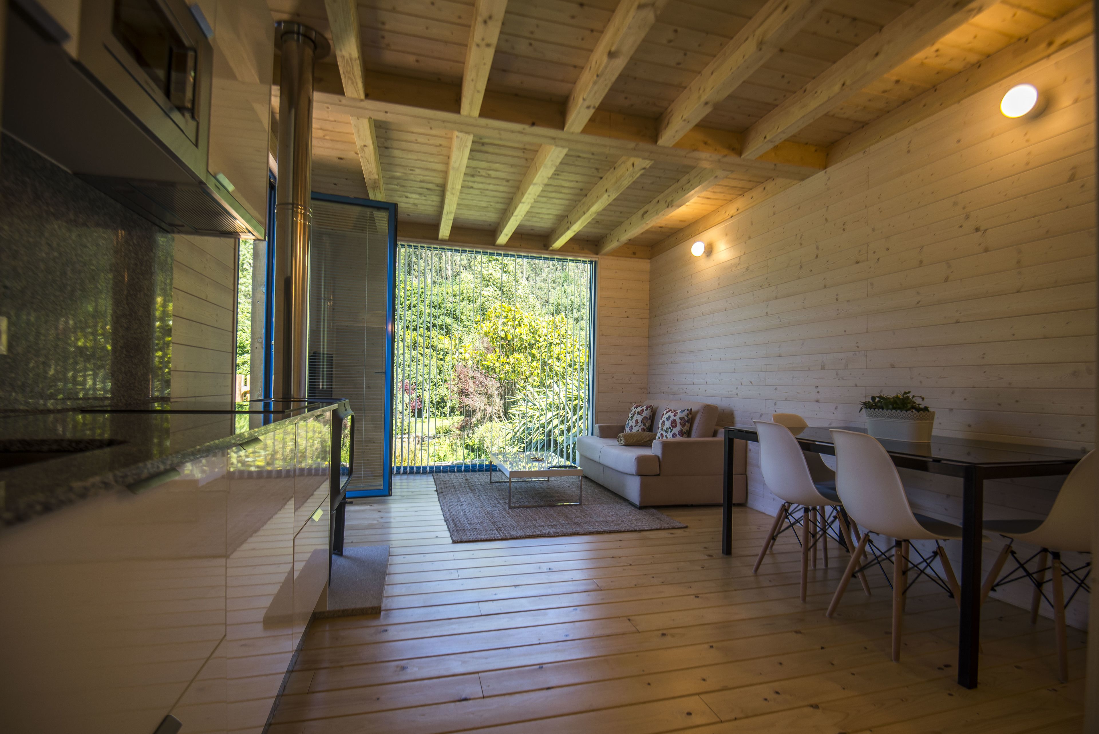 Un intérieur moderne avec un plancher en bois, une rambarde en verre, un canapé et un coin repas.