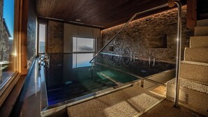 Een wellnessruimte met een glazen hottub, stenen muren en een houten plafond.