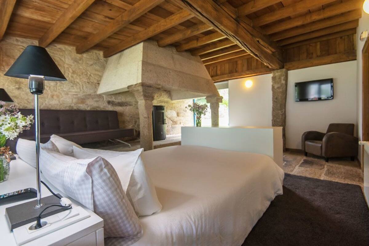 Une chambre à coucher avec un lit, une table de chevet, une lampe et un téléviseur fixé au mur.