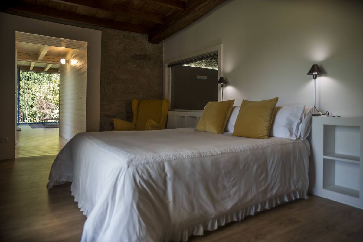 Une chambre avec un grand lit, une fenêtre, une porte donnant sur un balcon et une lampe sur la table de chevet.