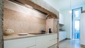 A kitchen with a stone backsplash, white cabinets, and a sink. - Santa Justa Prime Guesthouse (Lisbon)