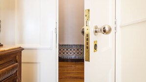 A room with a wooden dresser, a white door with a brass handle, and a patterned tile backsplash. - Santa Justa Prime Guesthouse (Lisbon)