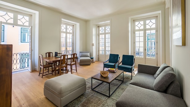 A spacious living room with a dining area, a sofa, a coffee table, and a balcony with a railing. - Santa Justa Prime Guesthouse (Lisbon)