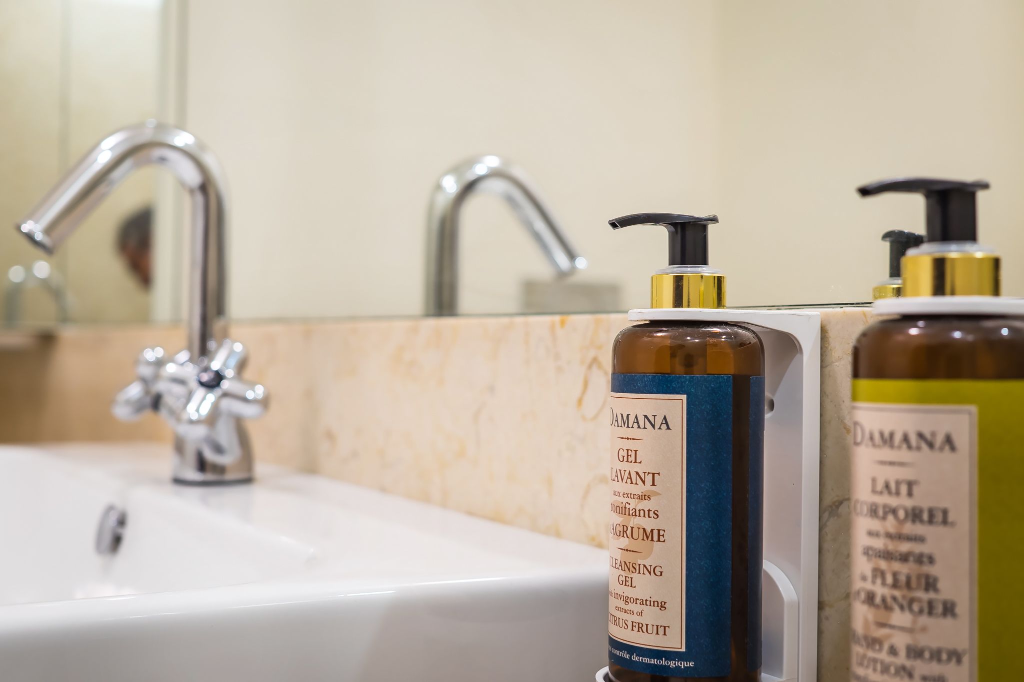 A bathroom sink with two bottles of DAMANA gel and a bottle of DAMANA body lotion.