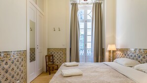 A hotel room with a large bed, a chair, a lamp, and a view of the outside through a door. - Santa Justa Prime Guesthouse (Lisbon)
