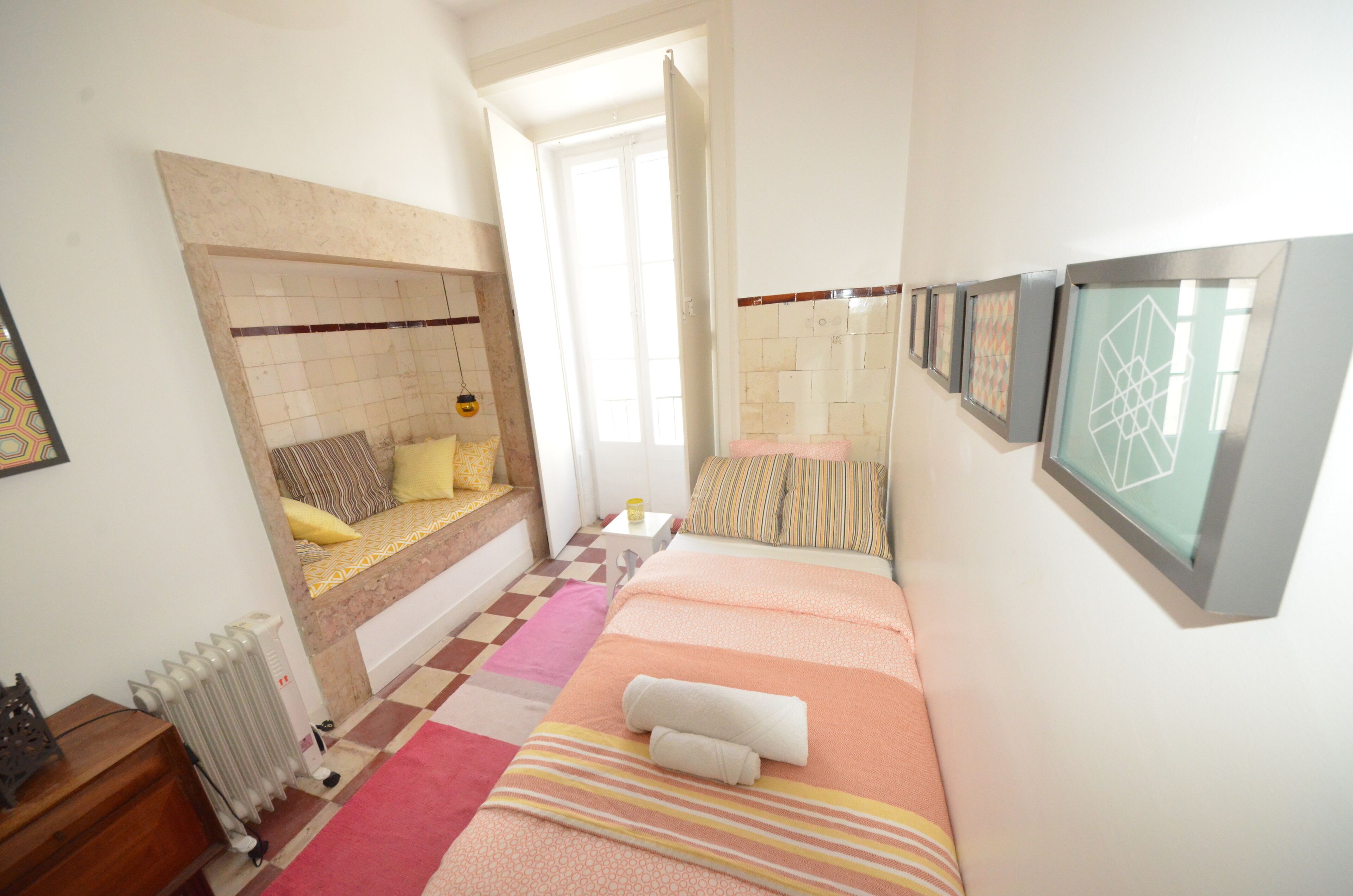 Een slaapkamer met een bed, een radiator, een geruite vloer en een deur naar een andere kamer.