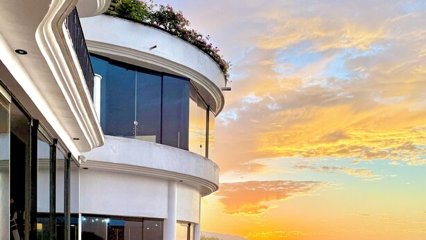 A modern building with a curved balcony overlooking a sunset. - Luxurious Oceanfront Estate on Vallarta's South Shore, Pool, Jacuzzi, Chef, Maid (Puerto Vallarta)