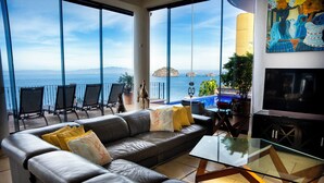 A modern living room with a leather sofa, glass coffee table, and a view of the ocean. - Luxurious Oceanfront Estate on Vallarta's South Shore, Pool, Jacuzzi, Chef, Maid (Puerto Vallarta)