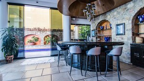 A modern kitchen with a bar area, stone walls, and a large window overlooking a garden. - Luxurious Oceanfront Estate on Vallarta's South Shore, Pool, Jacuzzi, Chef, Maid (Puerto Vallarta)