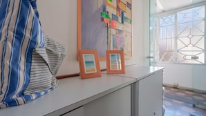 A room with a striped shirt on a white cabinet, a colorful abstract painting, and two framed pictures. - Casa Diaz (Cagliari)