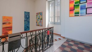 A hallway with artwork on the walls, a mailbox, and a window with a view. - Casa Diaz (Cagliari)