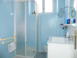 A bathroom with a glass shower enclosure, a white sink, and a toilet. - Casa Diaz (Cagliari)