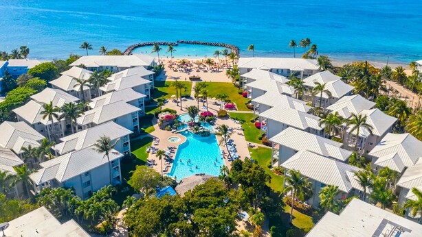 Ein Resort mit einem zentralen Schwimmbad, mehreren Gästezimmern und Blick auf den Ozean.