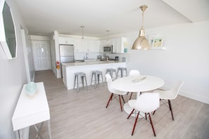 Enjoy meals at the central island with bar stools, or dine at the round table with white chairs.