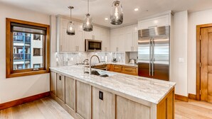 A modern kitchen with a large island, stainless steel appliances, and pendant lighting. - Centennial 2 Bedroom Condo Unit no. 13ab (Avon)