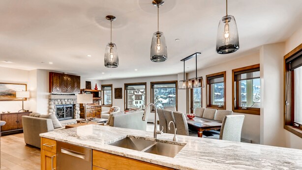 A spacious kitchen with a large island, wooden cabinets, and pendant lighting. - Centennial 2 Bedroom Condo Unit no. 13ab (Avon)