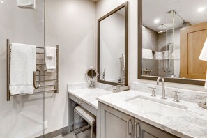 A modern bathroom with a glass shower enclosure, a vanity with a large mirror, and a double sink with chrome fixtures.