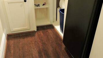 A compact kitchen with a black refrigerator, white cabinetry, and a wooden floor.