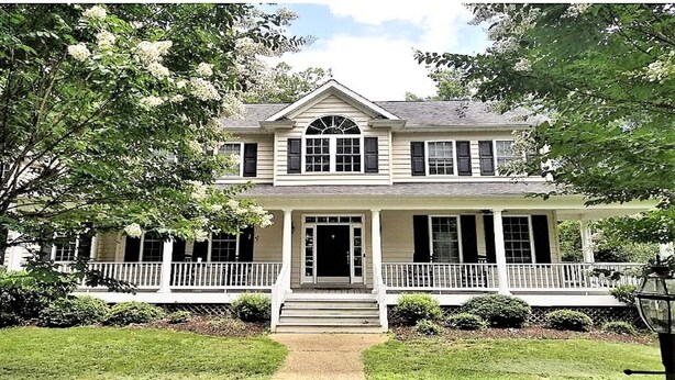 A two-story house with a front porch, a central entrance, and a symmetrical window arrangement.