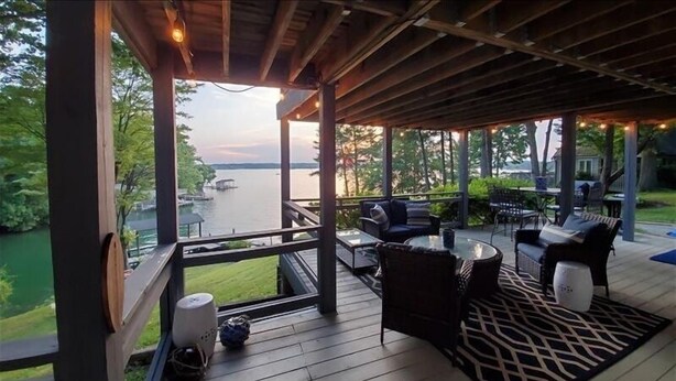 A covered deck with outdoor furniture, a view of a lake, and a wooden railing. - Hot Tub, Fireplace & Pet Friendly! Come Visit "Lake It or Knot"! (Huddleston)
