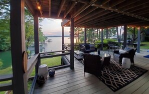 A covered deck with outdoor furniture, a view of a lake, and a wooden railing. - Hot Tub, Fireplace & Pet Friendly! Visit LAKE IT OR KNOT! (Huddleston)