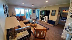 A living room with a sofa, a coffee table, a TV, and a fireplace. There is a dining table with chairs and a lamp. - Hot Tub, Fireplace & Pet Friendly! Come Visit "Lake It or Knot"! (Huddleston)