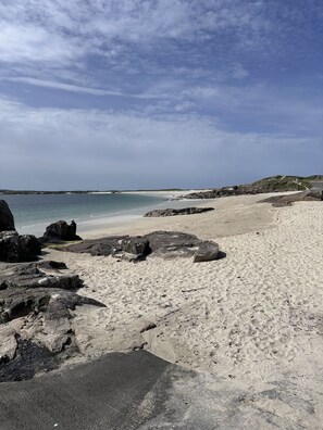 A beach with rocky outcrops and a clear sky.
