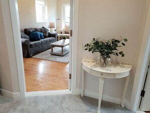 A hallway leading to a living room with a sofa, coffee table, and a potted plant.